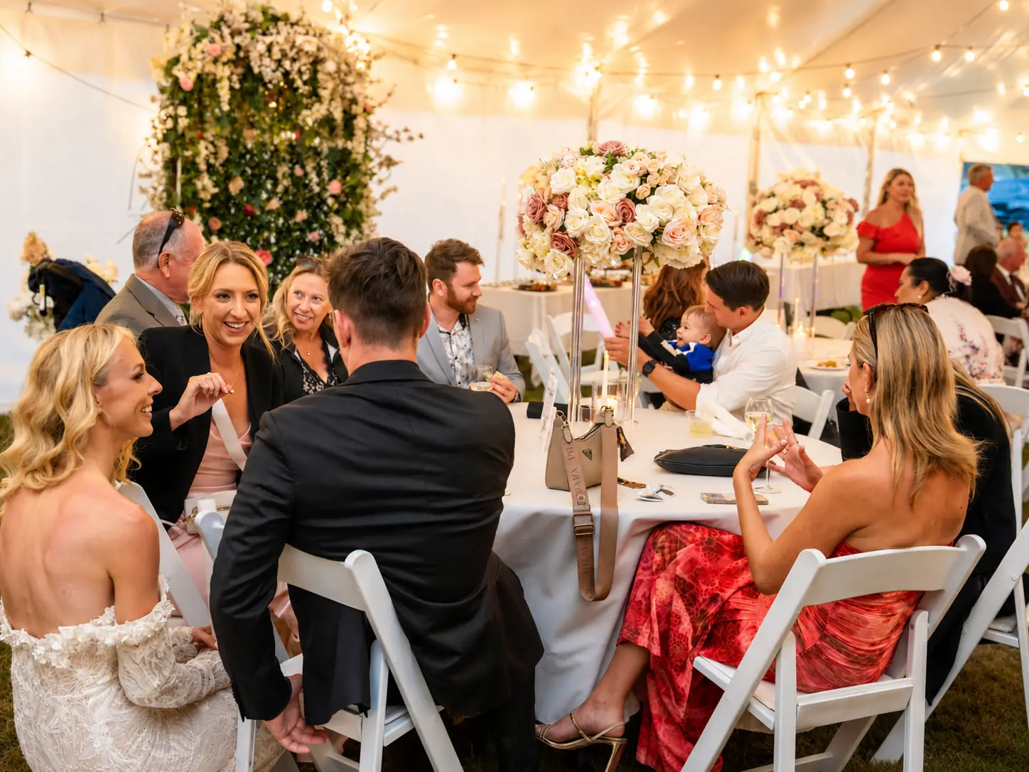 Guests sharing dinner and conversation beneath the marquee lights at Adeline Estate
