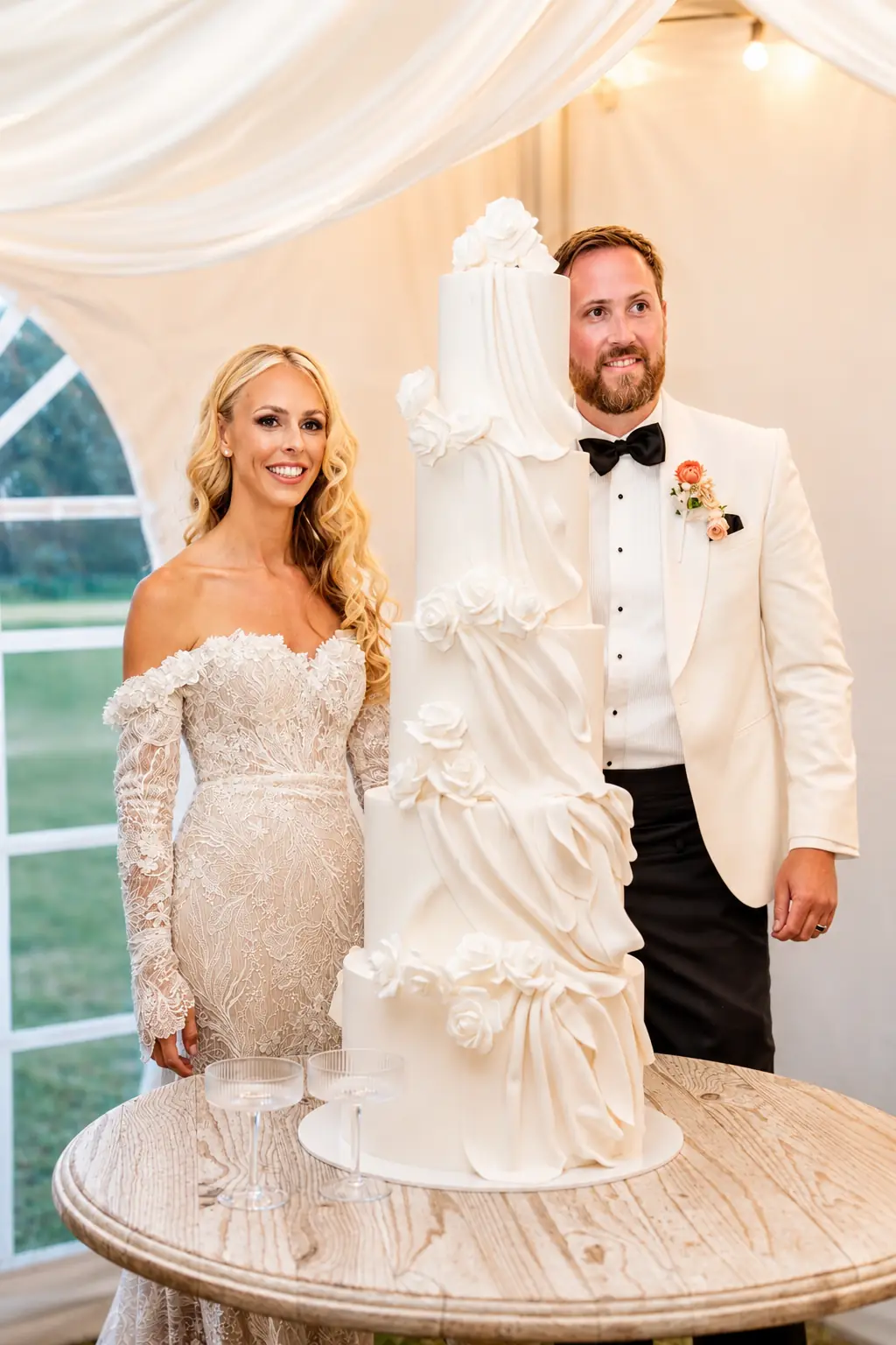 Couple beside a sculptural wedding cake inside the marquee at Adeline Estate