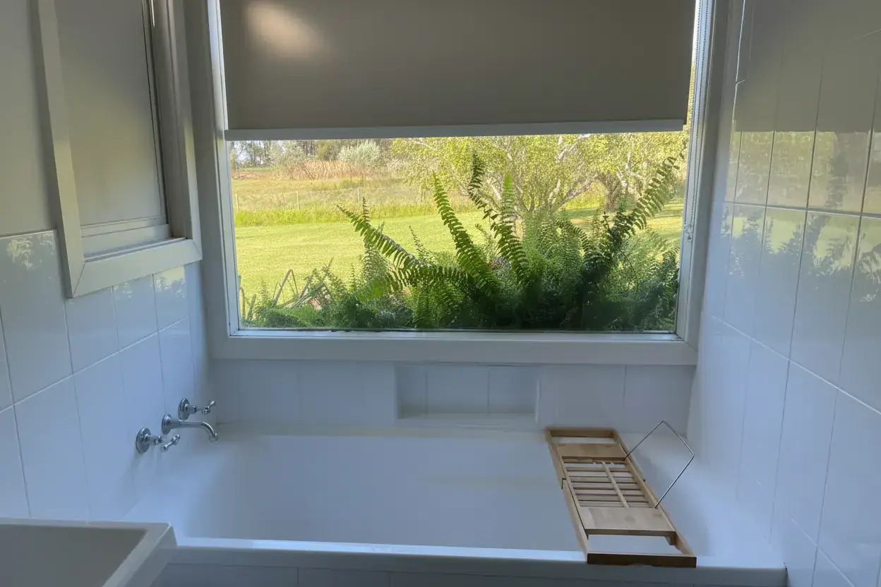 Freestanding bath beside a picture window looking out over gum trees at the Adeline Estate farmhouse