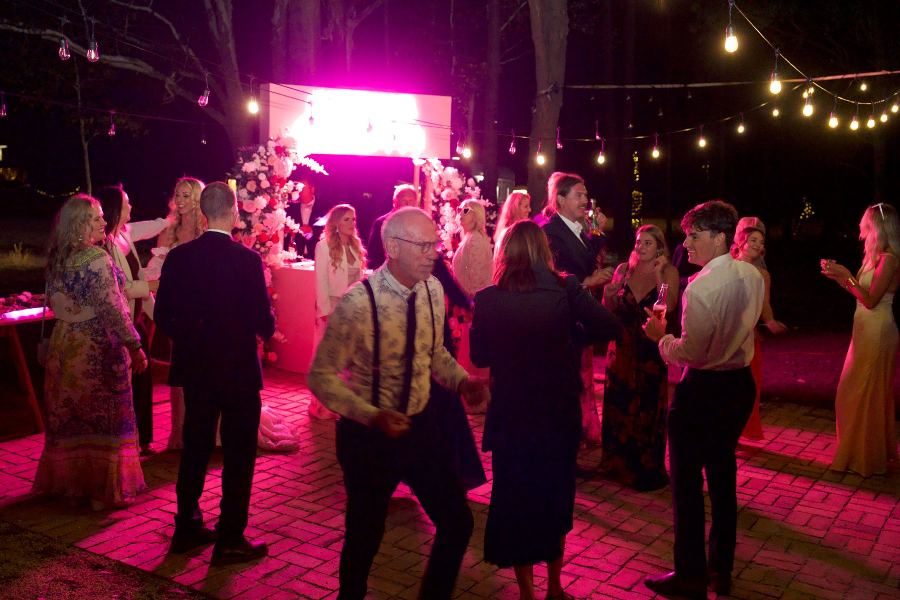 Guests dancing under festoon lights at night