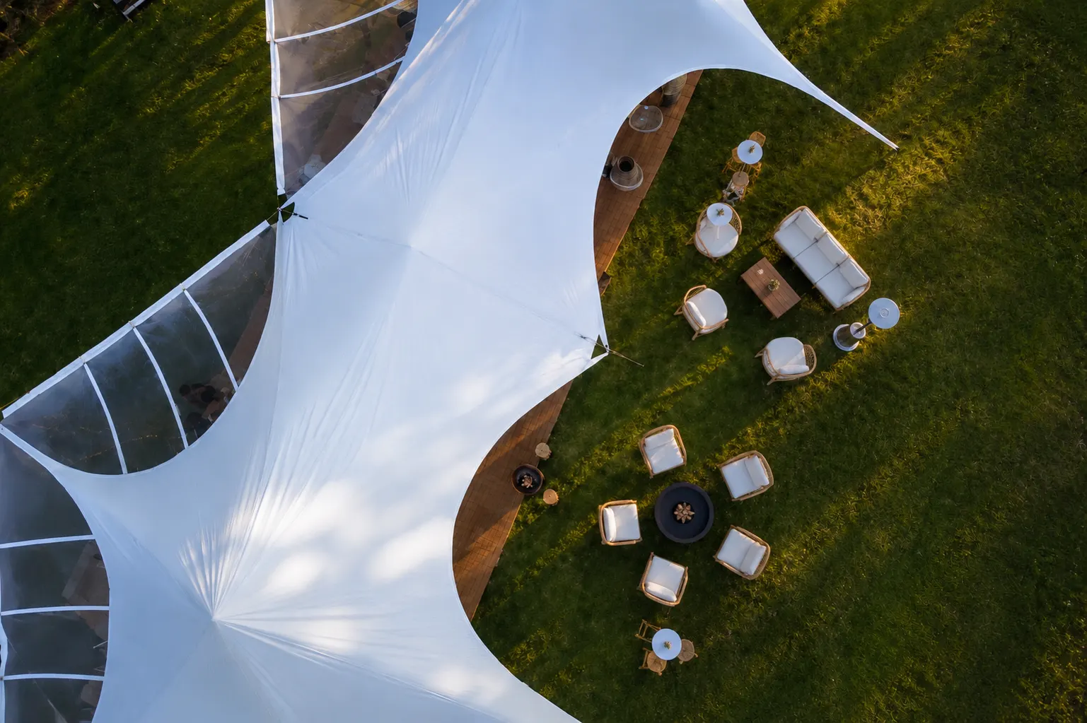 Spider marquee from above with a timber deck and lounge furniture on the lawn beside it