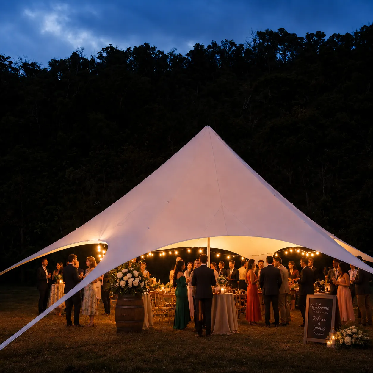Wedding guests under a lit spider marquee with festoon lights at dusk in the Hunter Valley